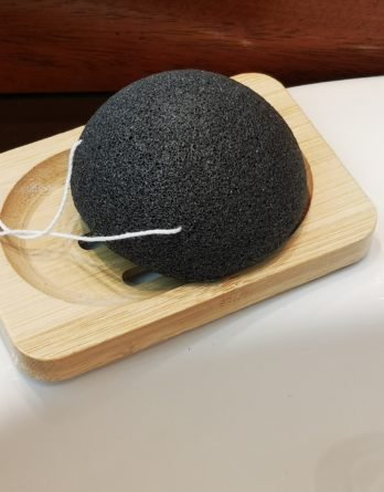 savon posé sur un gant exfoliant dans et un porte savon dans une sdb devant un miroir