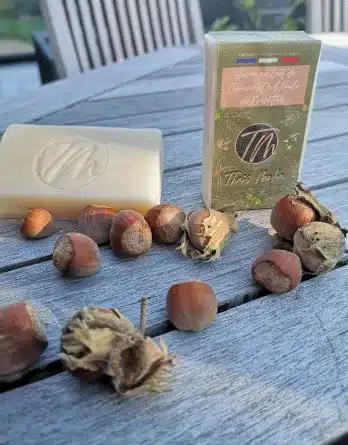 Savon shampoing 2 en 1 un à l'huile de noisettes présenté sur une tables en bois avec des noisettes